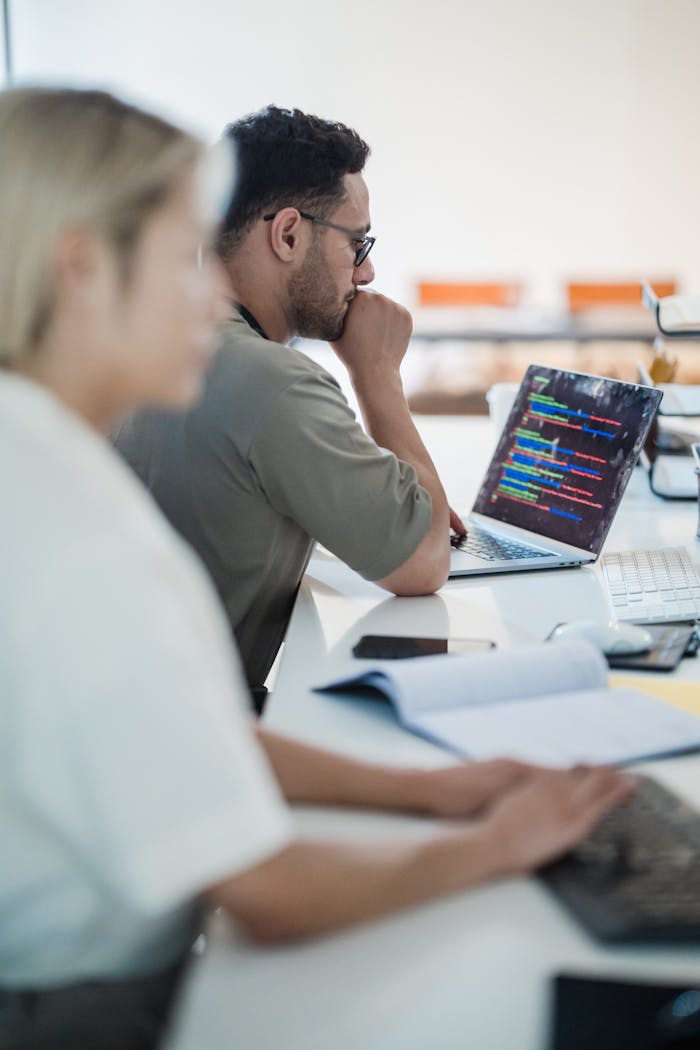 Home Two software developers work collaboratively on a coding project in a modern office setting.