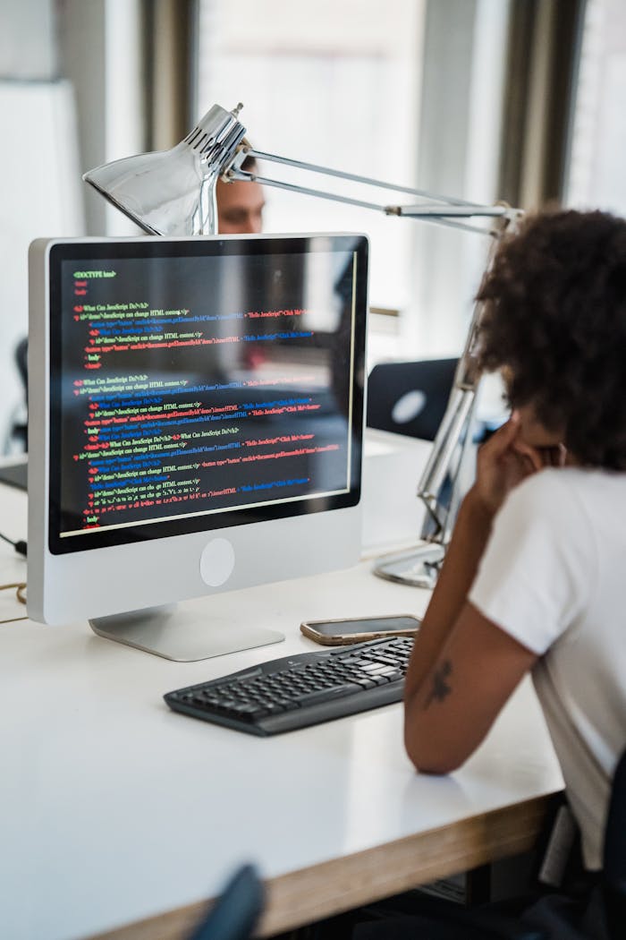 Services A female professional focused on coding at her office desk with a desktop computer.