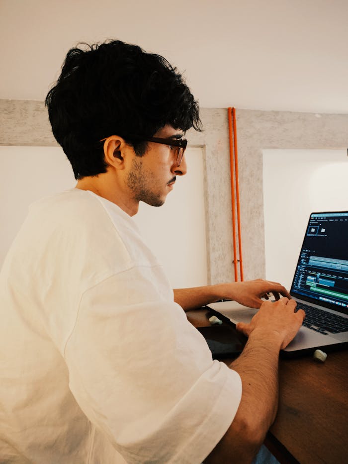 About Young man working on video editing software in a modern, cozy indoor setting.