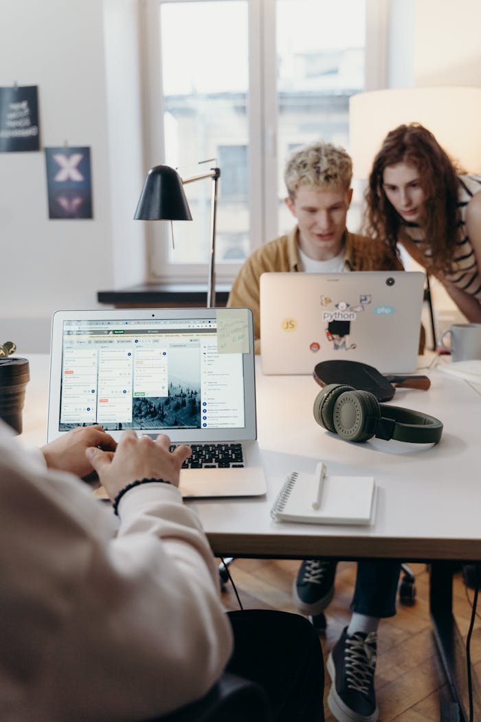 Home Young team collaborating at a modern workspace with laptops and headphones.