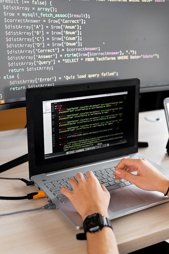 Services Person coding at a desk with laptop and external monitor showing programming code.